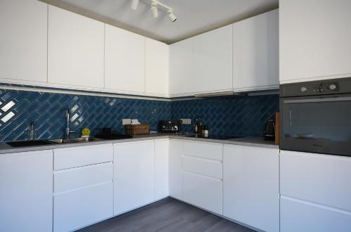 a kitchen with white cabinets and black appliances at Starfish Apartment in Beer