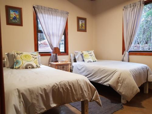 a bedroom with two beds and two windows at Kiepersol Cottages - Cottage A in East London