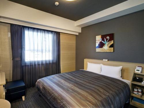 una camera d'albergo con letto e finestra di Hotel Route-Inn Nagahama Inter a Nagahama
