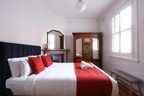 1 dormitorio con 1 cama grande con almohadas rojas en Discover The Rocks - Historical Terrace House en Sídney