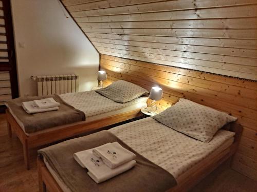 two beds in a room with a wooden wall at Apartamenty Pod Lipą in Lutowiska