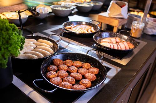 a buffet with trays of food on a stove at LOGINN Hotel Waiblingen in Waiblingen