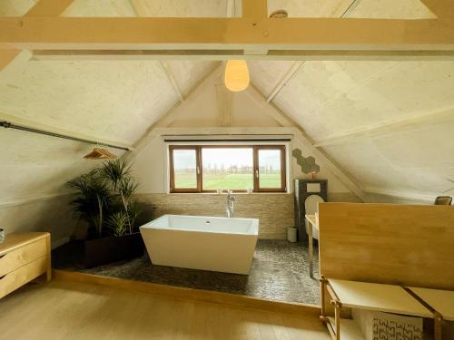 een badkamer met een wit bad op zolder bij Landelijk Huisje te Houtem in Veurne