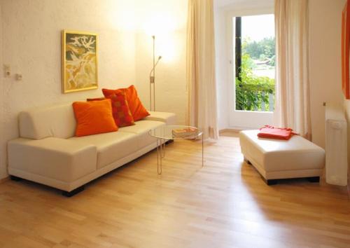 a living room with a white couch and orange pillows at Hotel Frankenschleif in Waldmünchen