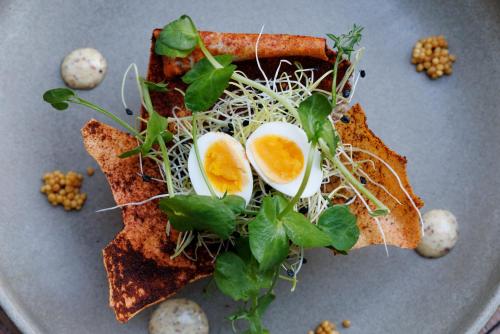 a plate of food with eggs and greens at Pillows Grand Boutique Hotel Reylof Ghent in Ghent
