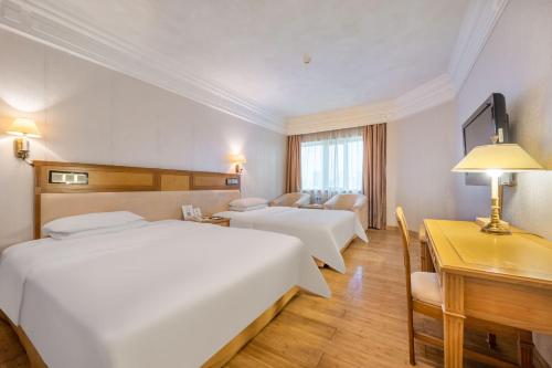 a hotel room with two beds and a desk at Hotel Silverland in Dongguan