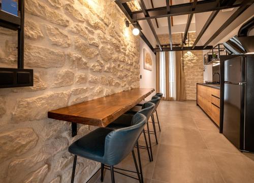 a dining room with a stone wall and a wooden table and chairs at Apartamentos Loliqui centro Alicante in Alicante