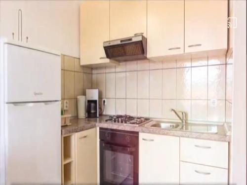una cocina con armarios blancos y fregadero en Apartments Snjezana, en Rab