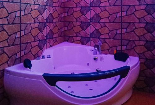 uma banheira roxa num quarto com uma parede de pedra em RedDoorz @ Sundance Mountain Resort Tampilisan em Zamboanga