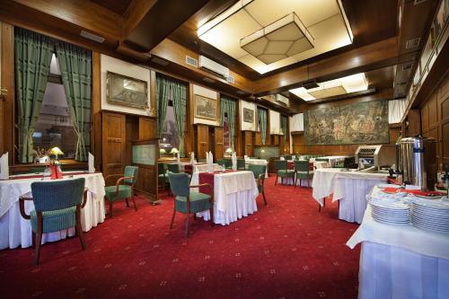 Brioni Boutique Hotel 4* في أوسترافا: غرفة طعام مع طاولات بيضاء وكراسي خضراء