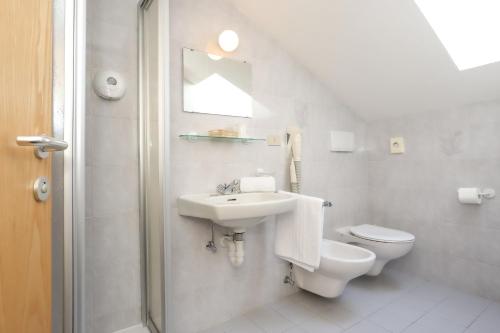 a white bathroom with a sink and a toilet at Hotel Langeshof in Anterivo