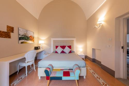 a bedroom with a bed with a desk and a chair at Palazzo Arco Cadura & Spa in Galatina