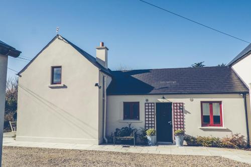 a white house with a large shadow on it at Maytown Cottage in Rosslare
