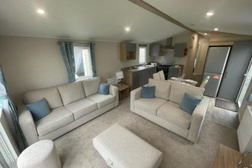 sala de estar con 2 sofás blancos y almohadas azules en Number 57 Brynteg en Caernarfon