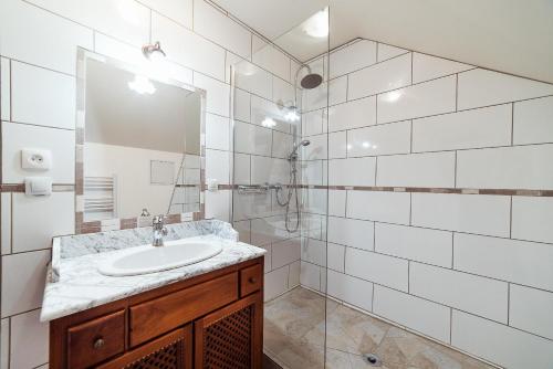 a white tiled bathroom with a sink and a shower at Studio confortable, parking et jardin in Buchères