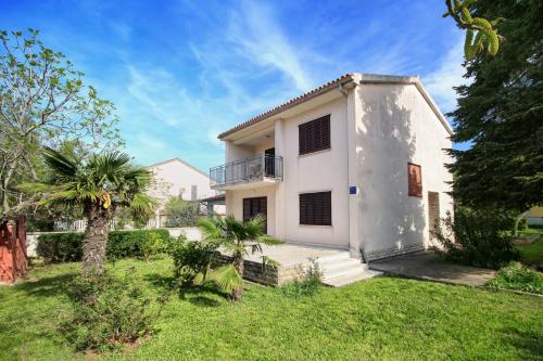 a white house with a green yard at Merlini in Medulin