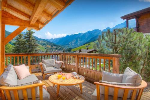 a deck with chairs and a table with a view of mountains at Chalet Timan - OVO Network in La Clusaz