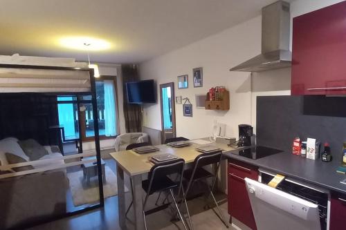 une cuisine avec une table et des chaises dans une pièce dans l'établissement Studio en altitude avec terrasse proche Gerardmer, à Xonrupt-Longemer