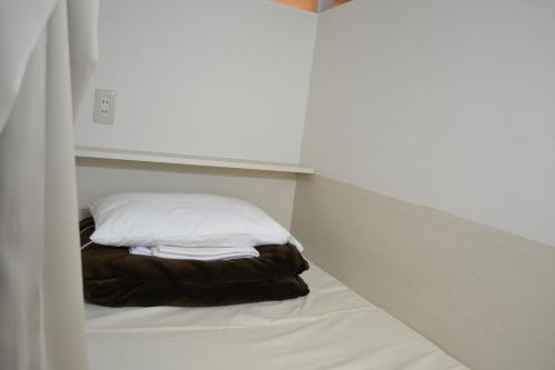 a small bed in a white room with a pillow at 1 Night 1980 Hostel Tokyo Asakusa Simple Stay in Tokyo