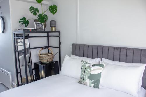 a bedroom with a bed with white pillows and a plant at Annex By The Sea in Littlehampton