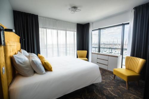 Cette chambre comprend un grand lit et une fenêtre. dans l'établissement Le Barracuda & Spa, Centre Port, pieds dans l'eau, vue mer, à Brest