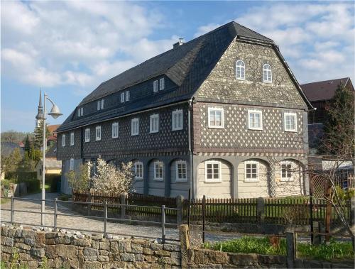 un grand bâtiment en briques avec un toit noir dans l'établissement Familienurlaub im gemütlichen Umgebindehaus, Seminarhaus, à Cunewalde