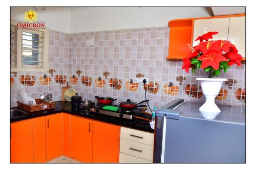 a kitchen with orange cabinets and a vase with red flowers at Hotel Omicron 1 BHK Studio room in Bengaluru