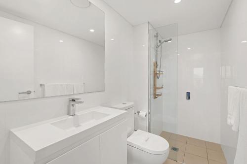 a white bathroom with a sink and a toilet at The Shoal in Shoal Bay