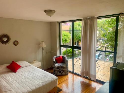 ein Schlafzimmer mit einem Bett und einer Glasschiebetür in der Unterkunft Satya Suites & Portal San Angel Flats in Mexiko-Stadt