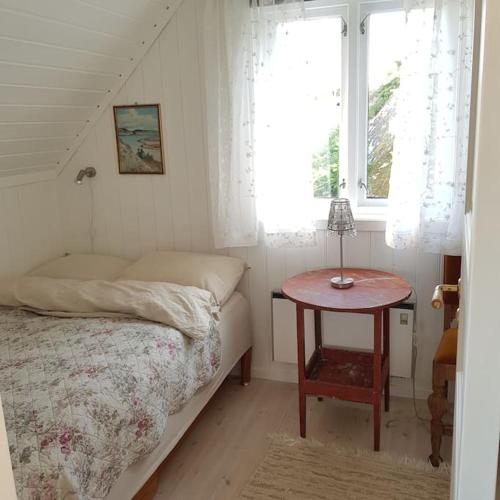 a bedroom with a bed and a table with a window at Lys og lettstelt leilighet med utsikt over byen in Sandefjord