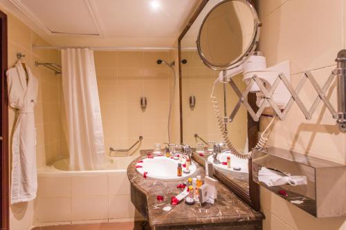 een badkamer met een wastafel, een spiegel en een bad bij Le Zenith Hotel & Spa in Casablanca