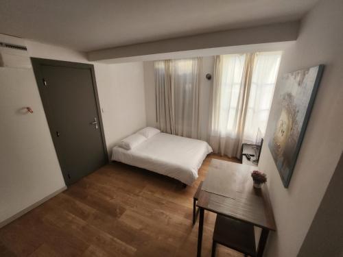 Cette petite chambre comprend un lit et une table. dans l'établissement Pied à terre tout confort, à Bar-le-Duc