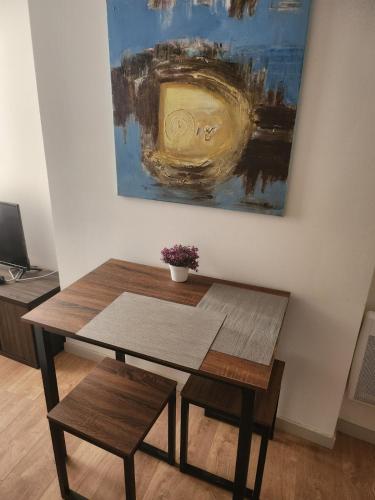 une table et un banc dans une pièce avec un tableau dans l'établissement Pied à terre tout confort, à Bar-le-Duc