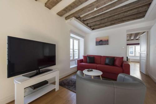 a living room with a red couch and a flat screen tv at Cactus in Paris