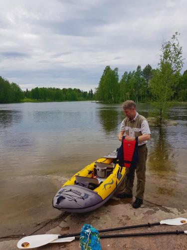 a man standing next to a boat on a river at Guesthouse Torppa in Korkeakoski
