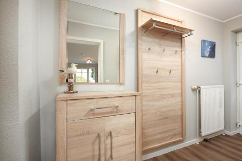 La salle de bains est pourvue d'une commode en bois et d'un miroir. dans l'établissement Bellevue 03, à Laboe