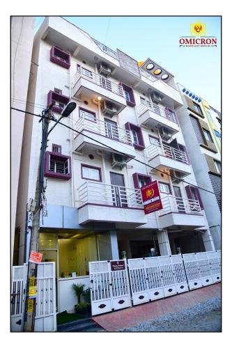 a large white building with balconies on a street at Hotel Omicron 1 BHK Studio room in Bengaluru