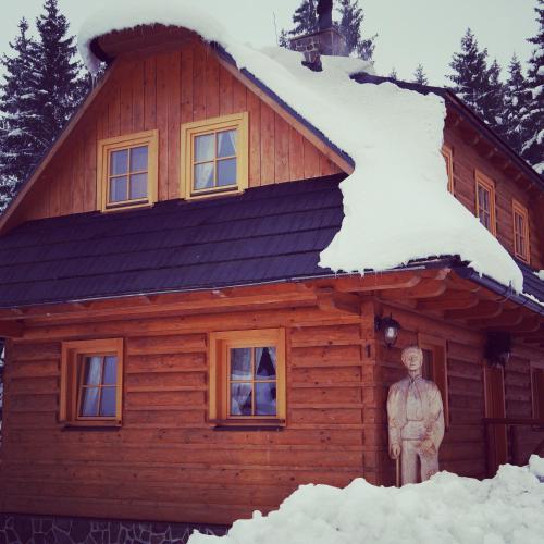 a statue of a man standing in front of a house covered in snow at Koliba u Kuba a rekreačné domy in Hruštín