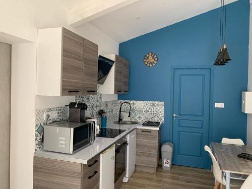 une cuisine avec des murs bleus et une porte bleue dans l'établissement Séjour détente et bien être avec SPA au gîte l Olipin, à Aubais