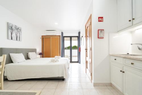 a white room with a bed and a kitchen at Apartamentos Vale de Carros by Umbral in Albufeira