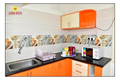 a kitchen with orange cabinets and a sink and a microwave at Hotel Omicron 1 BHK Studio room in Bengaluru