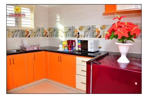 a kitchen with orange cabinets and a vase with a plant at Hotel Omicron 1 BHK Studio room in Bangalore