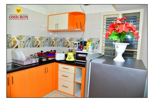 a kitchen with orange cabinets and a vase of flowers at Hotel Omicron 1 BHK Studio room in Bengaluru