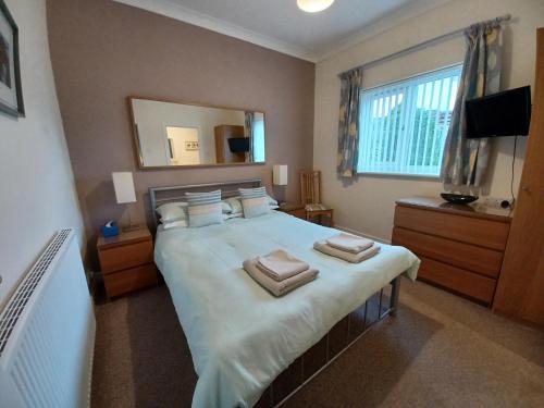 a bedroom with a large bed with two towels on it at Solway Retreat in Gretna