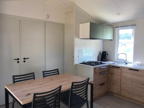 Bec-de-Mortagne的住宿－Mobile-home Pin，厨房配有木桌、椅子和炉灶。