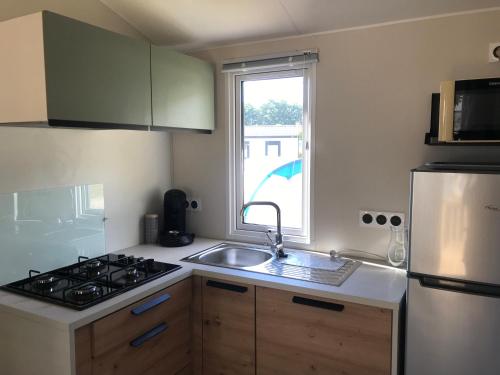 uma cozinha com um lavatório, um fogão e uma janela em Mobile-home Pin em Bec-de-Mortagne