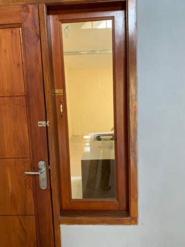 a wooden door with a mirror next to a sink at First Tasnim Village in Cibatok 1