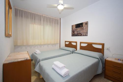 um quarto com 2 camas e toalhas em La Pinta - Fincas Arena em Benidorm