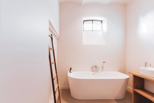 a white bathroom with a tub and a sink at Duisbeke Logies in Oudenaarde