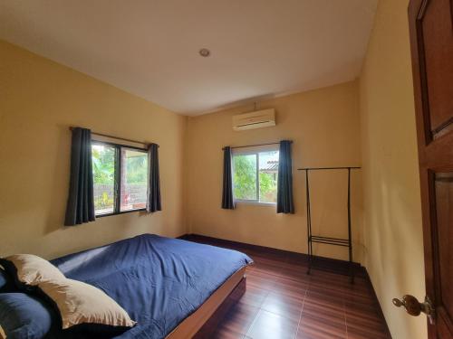 a bedroom with a bed and two windows at Ban Tai - Nice house in a quiet area 2 min from main road in Thong Sala